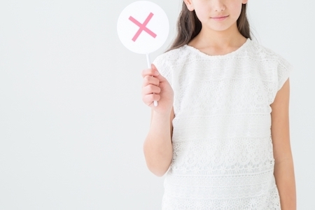 バツ印をしている女性